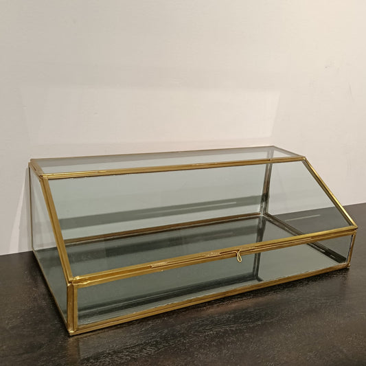 Glass display case with gold frame on a dark surface