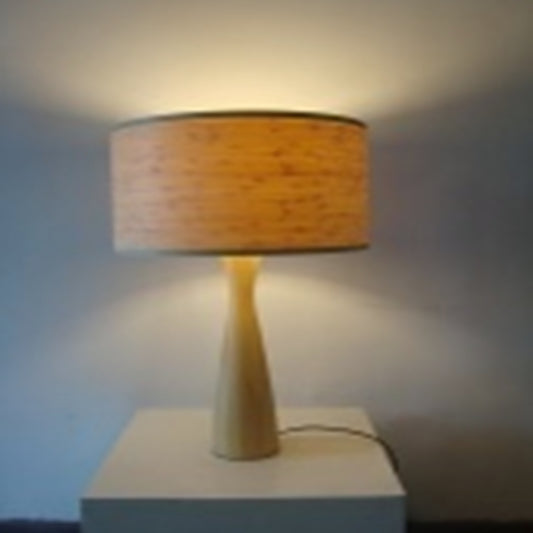 Table lamp with a yellow base and orange shade on a white surface against a blue wall.